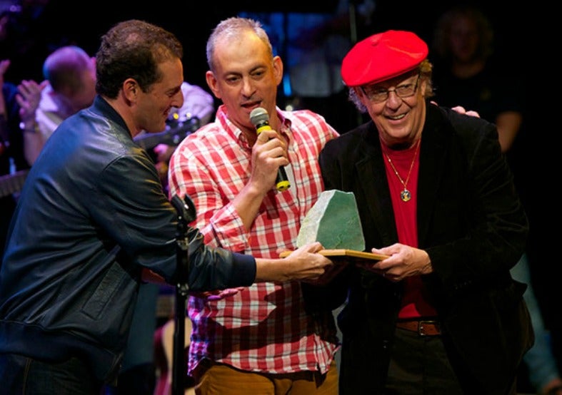 Rich Battista and Teddy Zambetti stand next to Bill Danoff who holds a microphone