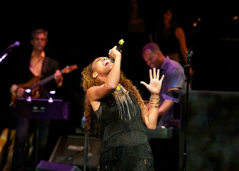 Danielle Carter performs on stage with her head tilted back and microphone raised above