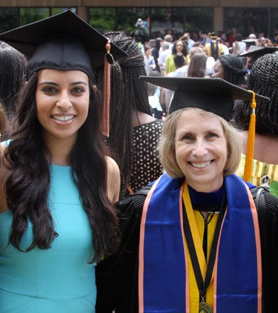 Marie Diener-West and Christina Marie Hanna, both wearing graduation caps, smile for the camera. 