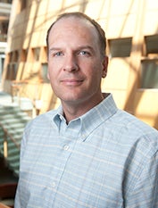 Kurt Carlson, dressed in a button-down, smiles for the camera.