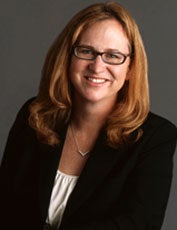 Laura Donohue, dressed in a black blazer and white blouse, smiles in a headshot.