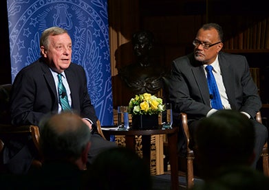 Sen. Richard Durbin (D-Illinois) and Edward Montgomery, both seated onstage, speak to the audience.