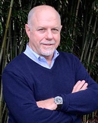 Timothy J. Jorgensen stares into the camera outside with arms folded.