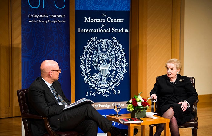 Joel Hellman and Madeleine Albright onstage with banners for the School of Foreign Service and the Mortara Center