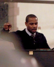 Nolan Williams stands behind piano directing choir