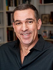 Richard Ortiz, in a black top, smiles in a headshot.