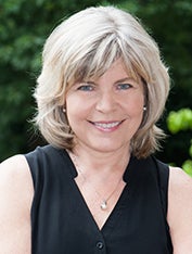 Kathryn Temple, in a black top, smiles in a headshot.