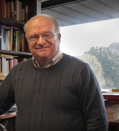 John Tutino smiles for the camera against a bookshelf in the background.