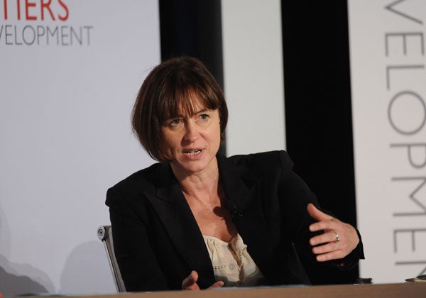 Sarah Cliffe speaks while seated in front of a backdrop