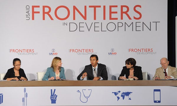 Emilia Pires, Nancy Lindborg, Kaj Larsen, Sarah Cliffe and Mark Schneider speak on a panel in front of a backdrop