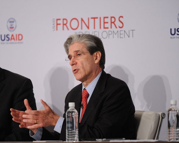 Julio Frenk speaks while seated in front of a backdrop