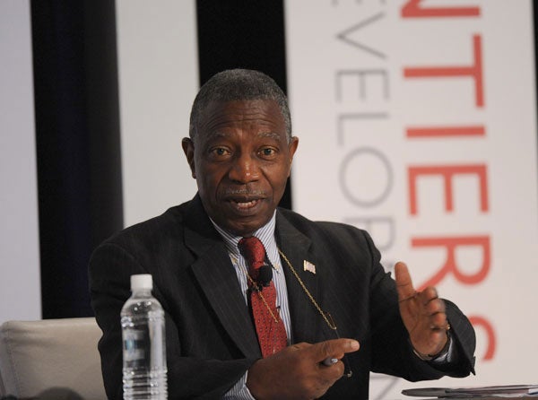 Walter Gwenigale speaks while seated in front of a backdrop