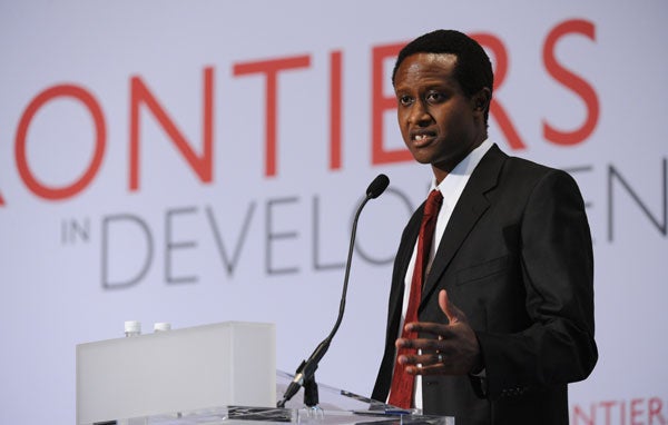 James Habyarimana speaks into a microphone while standing in front of a backdrop