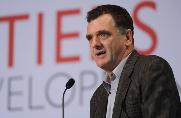 William Jack speaks into a microphone while standing in front of backdrop