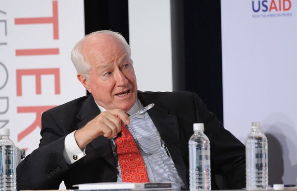 Jim Kolbe speaks with head tilted slightly in front of a backdrop