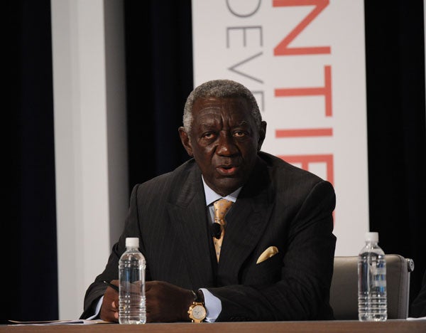 John Kufor speaks while sitting in front of a backdrop