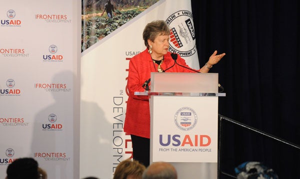 Carol Lancaster speaks at a podium in front of a backdrop