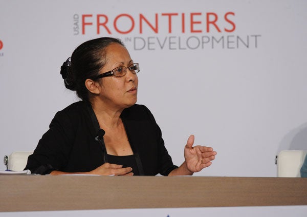 Emilia Pires speaks while seated in front of a backdrop