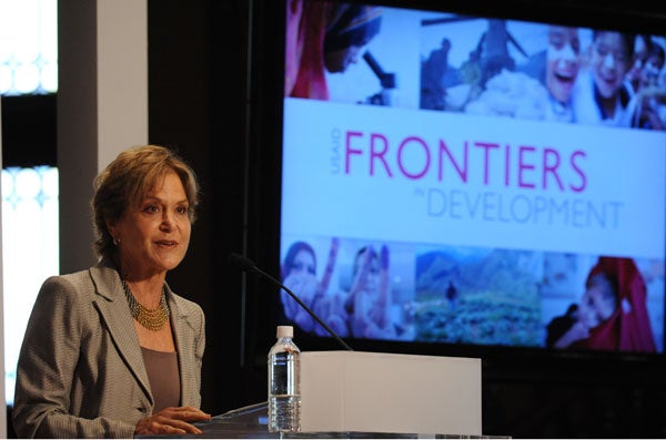 Judith Rodin speaks in front of a backdrop with projection