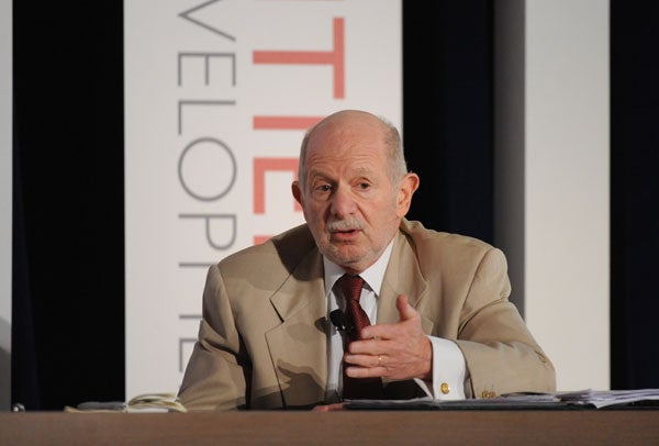 Mark Schneider speaks while seated in front of a backdrop