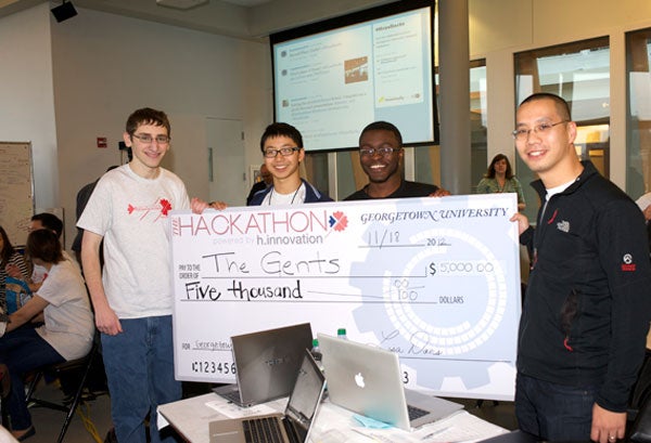 A team of competitors holds the large check worth $5,000 while smiling