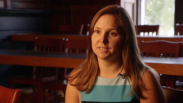 Joanna Lewis, in a bold striped dress, speaks to the camera.