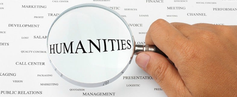 A photo of a hand holding a magnifying glass emphasizing the word "Humanities."