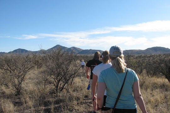 Georgetown students walking among brush towards mountains