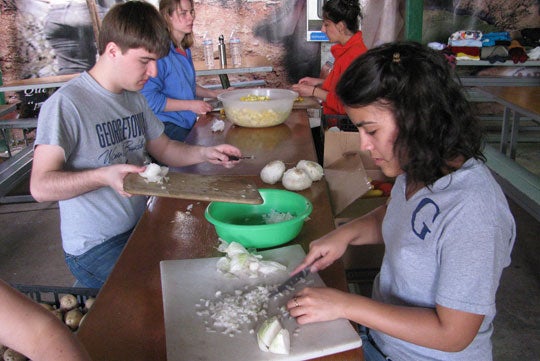 Pat Curran and Bonnibel Rosario chop up onions and place other food into bowls on a table