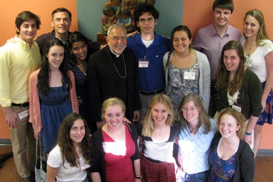 Students and Kevin O'Brien pose for a photo in a house with Gerald Kicanas