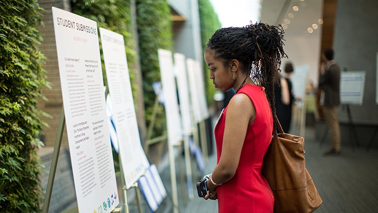 Woman looking at posters at the Undergraduate Bioethics Research Showcase 