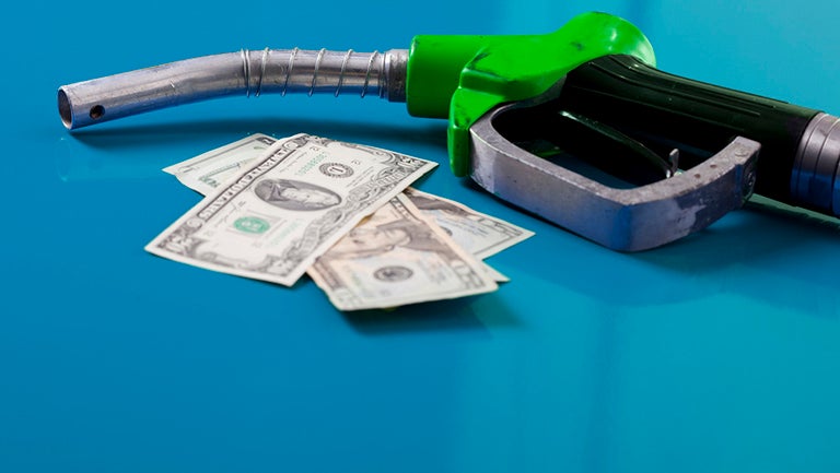 image of photo with money spread out near a gas tank nozzle