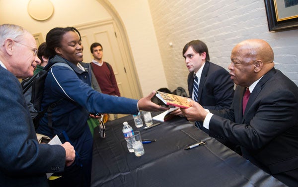 Andrew Aydin and John Lewis sign books while speaking to members of the university community outside Riggs Library