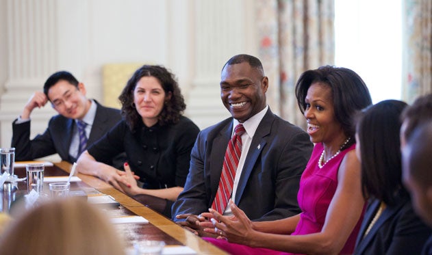 Rodney Lewis and Michelle Obama, both smiling, sit at a table together.