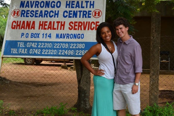 Sarah Lloyd puts her arm around Thomas Brooke while the pair pose beside a sign for Navrongo Health Research Centre in Ghana 