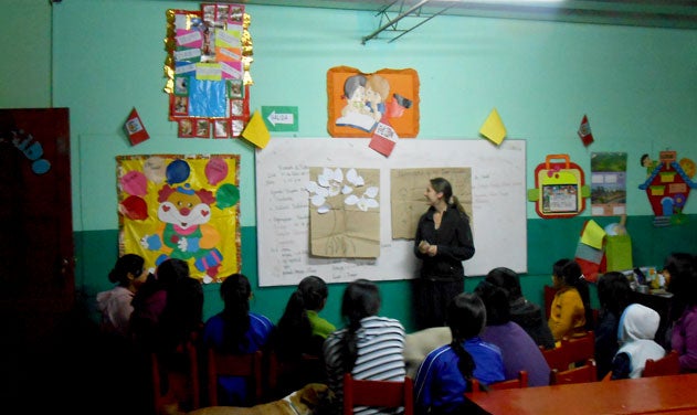 Emily McGinnis standing in front of poster, teaches youth in Peru