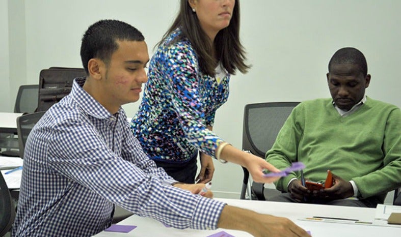 Alberto Morales sits at a table with two others working on a project