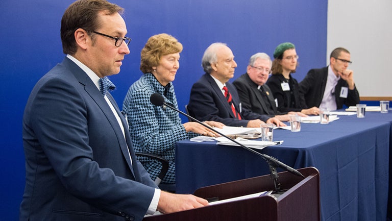 Panelists sit at a table onstage and discuss the response of religious actors to climate change.