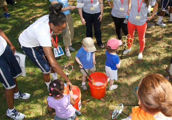 Women's basketball player Logan Battle (C'16) helps kids at the annual Hoya Fall Picnic create bubbles on White-Gravenor Lawn.