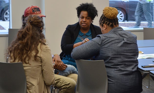 A woman speaks to 3 other women while seated at a table