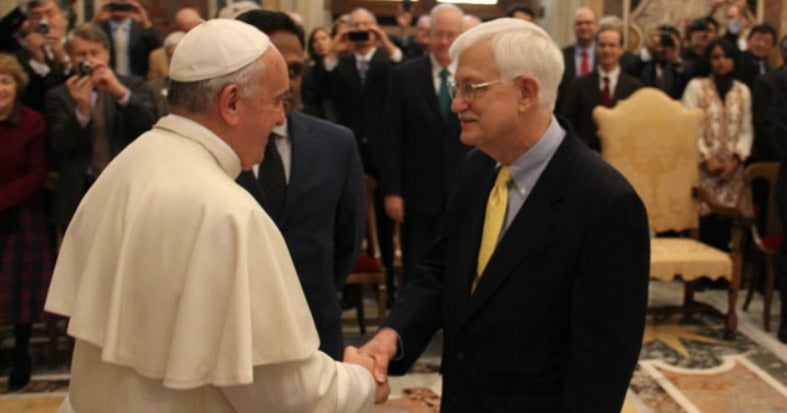 Pope Francis and Tom Farr shake hands.