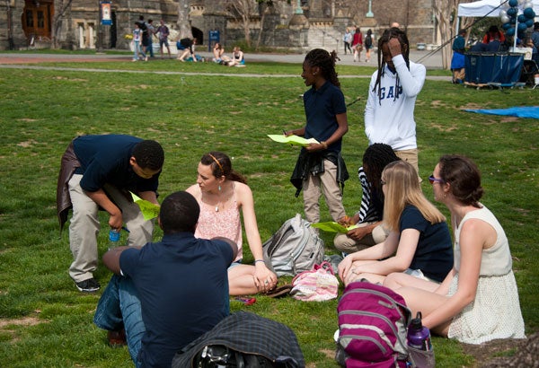 Students gather, some seated, some standing, on Copley Lawn while asking questions of an adult