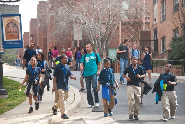 Students with lanyards on walk down Library Walk guided by a man in the middle