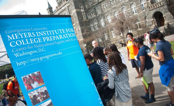 Students stand in Healy Circle next to a pop-up banner that says Meyers Institute for College Preparation