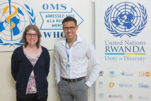 Laura Shrum and Kevin Diasti stand in front of a WHO (World Health Organization) sign in Rwanda