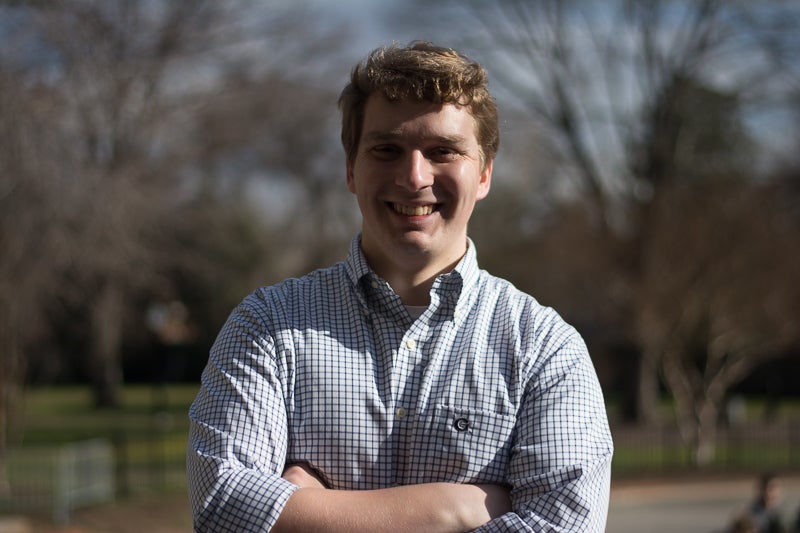 Andrew Debraggio smiles for the camera with his arms crossed.